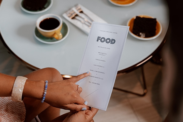 Person holding and pointing to a paper restaurant menu.
