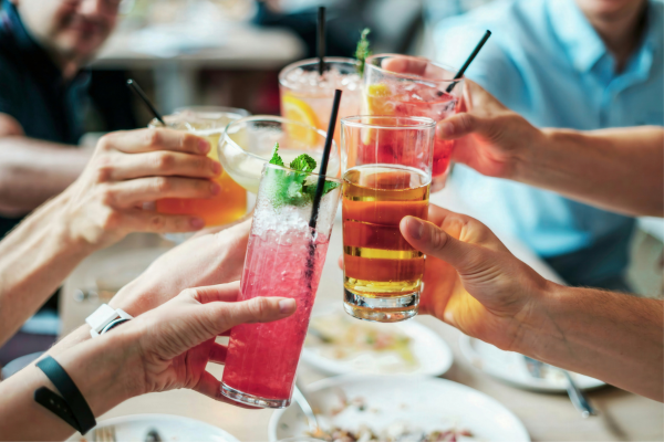 multiple hands clinking various drinks together